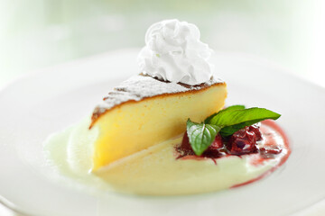 Serving of cheesecake in a plate with cream sauce and fruit