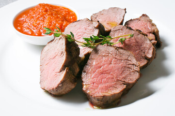 Serving of juicy steak with tomato sauce on a white plate
