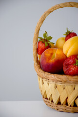 Composition of fresh fruits and berries in wicker basket cutted on half. Farm organic food market background.