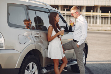 Fototapeta na wymiar Cute couple in a city. Lady in a white dress. People standing near car