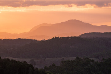 Pôr-do-sol na região serrana do Estado do Espírito Santo, Brasil, mostrando vales e morros cobertos de mata.