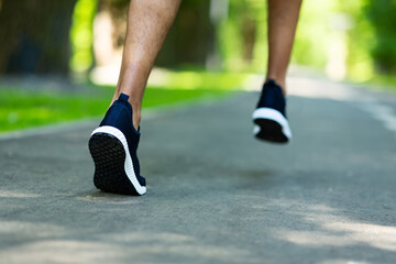 Fototapeta na wymiar Cropped view of marathon runner working out at park in morning, close up of legs