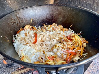 noodles with chicken are fried in a pan