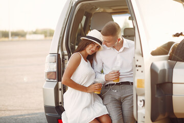 Cute couple in a city. Lady in a white dress. People with a lemonade near car
