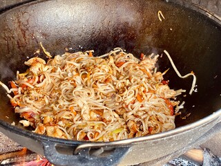 noodles with chicken are fried in a pan