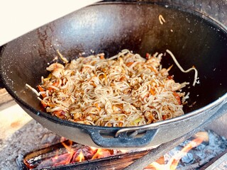 noodles with chicken are fried in a pan