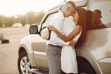 Cute couple in a city. Lady in a white dress. People standing near car