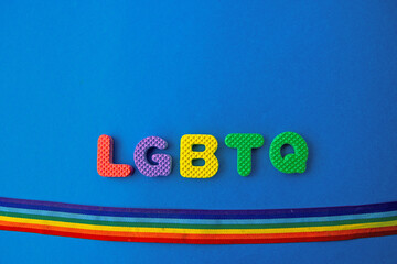 colored letters with word LGBTQ and rainbow ribbon flag on blue background
