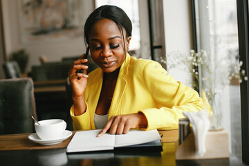 Elegant black woman. Lady in a yellow jacket. Businesswoman working in a office
