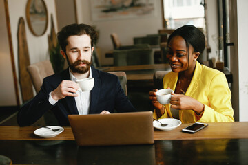 Handsome man in a black suit. Woman in a yellow jacket. Businessman working in a office