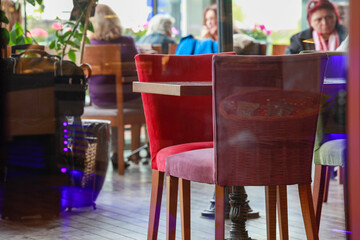 Two empty chairs and a table in a cafe with out of focus background.