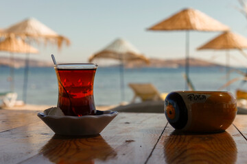Glass of tea on the wooden table with umbrella and sea background. Tea at the beach. Summer...
