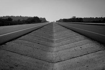 Black and white shot of a highway from the middle of the road. Open road ahead, endless road blur for concept in black and white. Road leading into the distance in b&w colors.