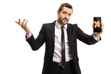 Upset young man in a suit holding a broken mobile phone with a band-aid