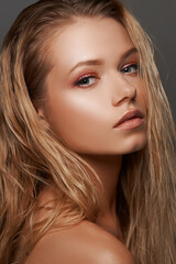 Fototapeta premium Closeup face fashion beauty portrait of young beautiful caucasian blonde woman with straight hair and makeup posing against gray background.