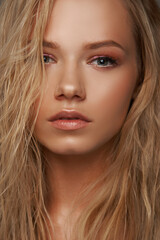 Fototapeta premium Closeup face fashion beauty portrait of young beautiful caucasian blonde woman with wet hair and makeup posing against gray background.