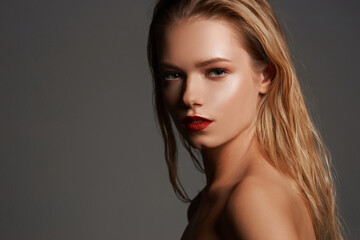 Fototapeta premium High fashion closeup beauty portrait of young stunning woman with long straight blonde hair, perfect makeup and red lips against gray background