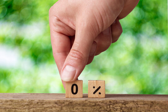 male hand lays out wooden cubes with numbers on a green background. zero percent. overpayment loan