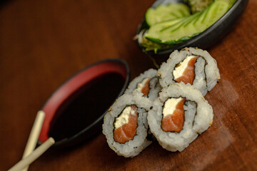 Sushi uramaki com salmão cru e cream cheese acompanhado de shoyu, salada de pepino e broto de feijão