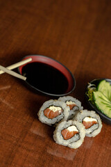 Sushi uramaki com salmão cru e cream cheese acompanhado de shoyu, salada de pepino e broto de feijão