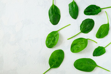 Fresh spinach leaves in a black bowl on a light surface. Fresh greens. Vegetarianism, healthy eating concept. Horizontal orientation, selective focus. View from above, copy space.