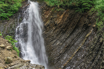 waterfall falling from a rock in a mountain forest