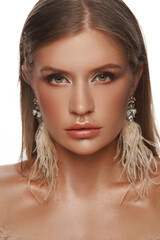 Girl fashion model with long straight hair wearing graceful feather earrings. Cosmetics and female accessories