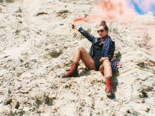 Model with american flag on her neck sitting and fires red colored smoke