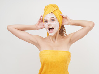 Surprised Young woman with cream mask on face with towel on the hair