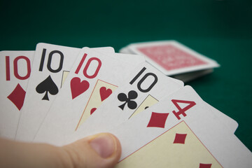 Someone holding some cards from the poker deck on green background