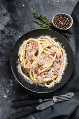 Obraz na płótnie Canvas Carbonara pasta, bucatini with pancetta, egg, parmesan cheese and cream sauce. Black background. Top view