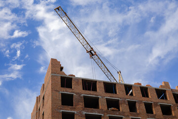 Industrial and construction concept. Construction site with modern building and cranes against blue sky.