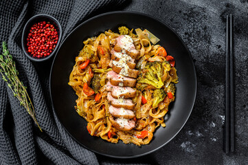 Stir fry wok noodles with grilled duck breast. Black background. Top view