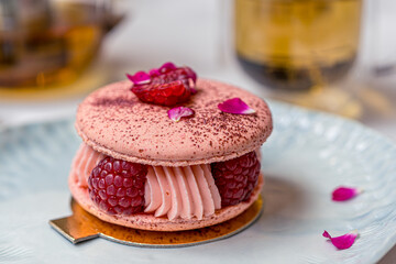 Beautiful Pink Raspberry Macaron cookies on blue plate. Healthy food. Blue table background. Top view.