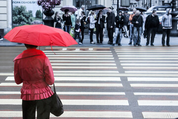 a woman with a red umbrella at a pedestrian crossing
