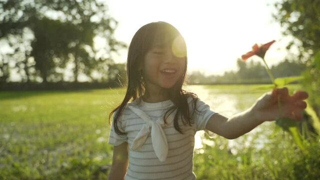 lovely asian daugther giving flower to her mother while playing in the field
