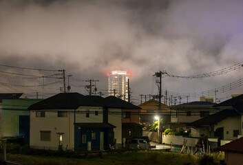 Tall building towers over quiet residential neighborhood with dramatic clouds just after sunset