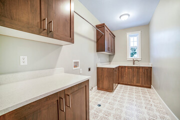 Kitchen interior with brown wooen cabinets white countertops sink and window