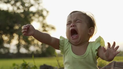 portrait close up of unhappy baby crying outdoor in the park
