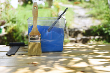 Painter's brush, blue paint pot and wooden shutter in the garden.