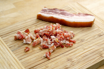 streaky bacon whole and cut into cubes on a wooden chopping board, selected focus, narrow depth of field