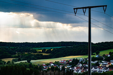 An electricity pylon in front of a cloudy sky flooded with sun rays.

The focus of this picture is...