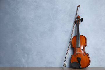 Beautiful violin and bow on wooden table near light blue wall. Space for text © New Africa