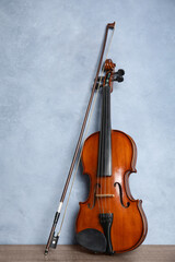 Obraz na płótnie Canvas Beautiful violin and bow on wooden table near light blue wall