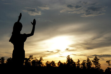 silhouette of a woman asking for blessings from God Evening sun background