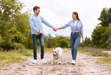 Portrait of happy young couple walking with their labrador