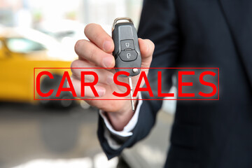 Salesman with key in car dealership, closeup