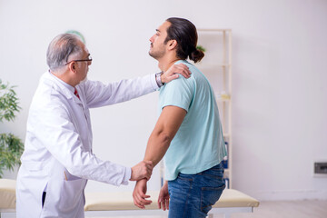 Young back injured man visiting experienced male doctor