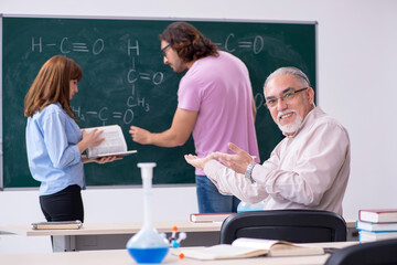 Old chemist teacher and two students in the classroom