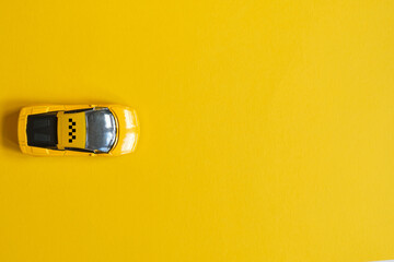 Toy taxi car on a yellow background with copy space.